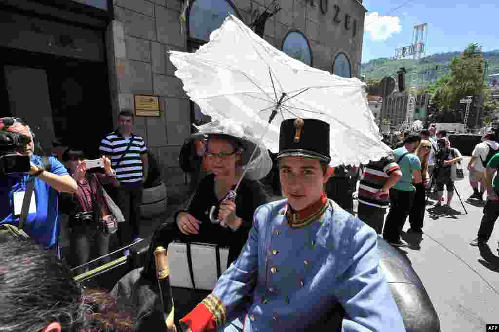 Tourists dressed in period costumes pose for photos inside a replica of the "Graf & Stift" car, in front of the town museum, at the street corner in downtown Sarajevo where Gavrilo Princip assassinated Austro-Hungarian heir to the throne Archduke Franz Ferdinand in 1914. (AFP/Elvis Barukcic)