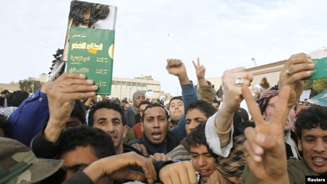 Protesters hold up a destroyed copy of dictator Muammar Qaddafi's "Green Book" as they chant antigovernment slogans in Tobruk on February 22.