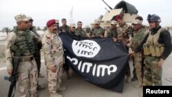 Iraqi security forces stand with an Islamic State flag which they pulled down in the city of Ramadi on February 1. The extremist group has suffered significant losses in Iraq and Syria in recent months.
