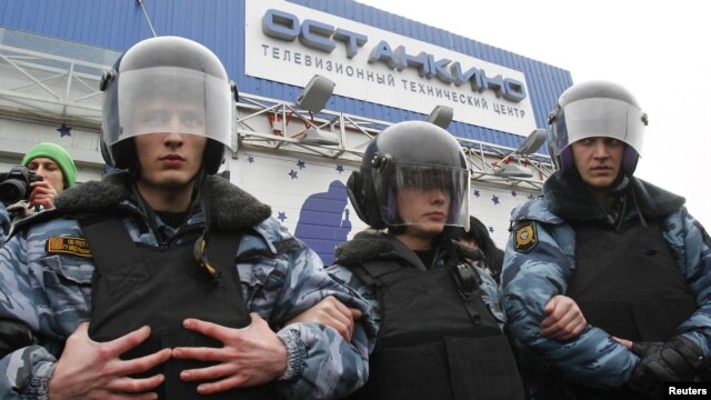 Riot police guard the Ostankino television tower in Moscow during a protest over the NTV program that alleged anti-Putin protesters were paid to attend demonstrations.