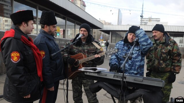 Cossack militia members (left) check out street musicians at the entrance to a Moscow subway station on November 14.