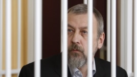 Former opposition presidential candidate Andrey Sannikau sits in a cage during a court hearing in Minsk in April.
