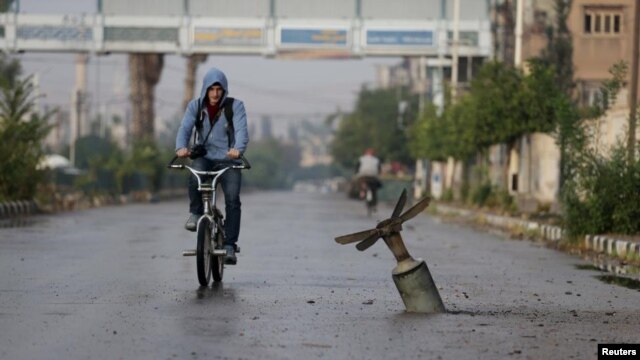 A resident rides his bicycle near what activists said was an exploded cluster bomb shell in the town of Douma, north-east of Damascus in November.