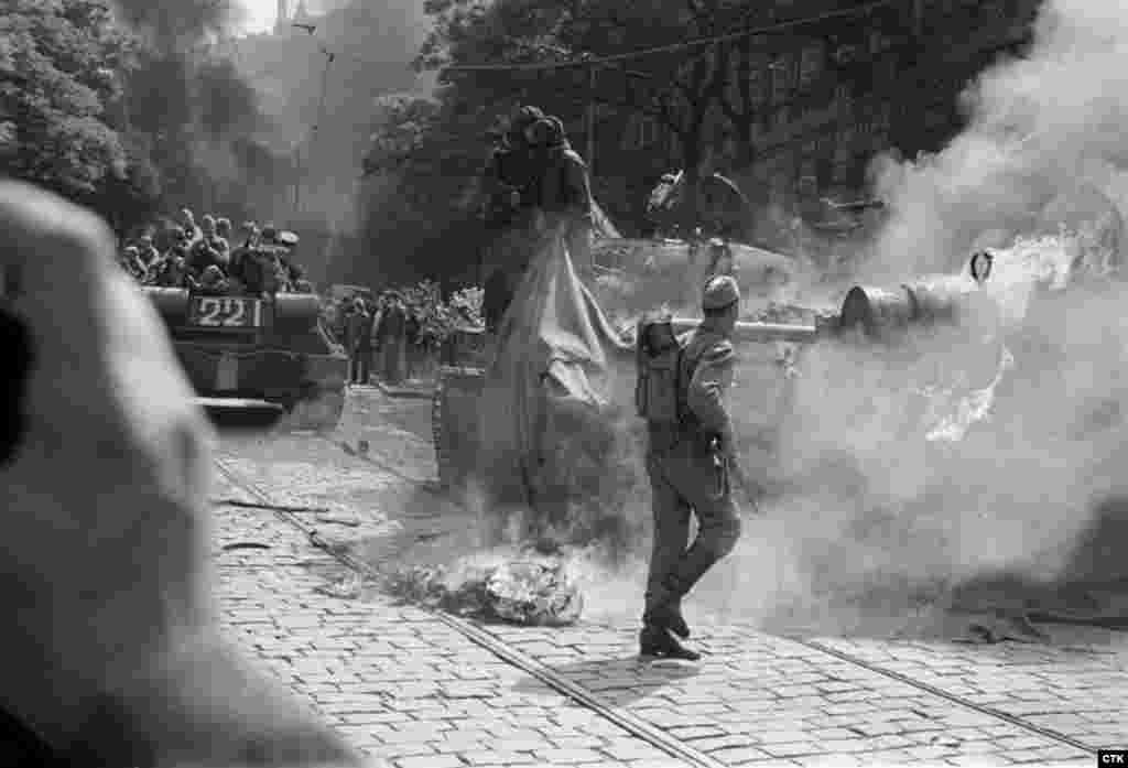 Soviet soldiers try to extinguish a burning tank set on fire by protesters near the Czechoslovak Radio headquarters in Prague.