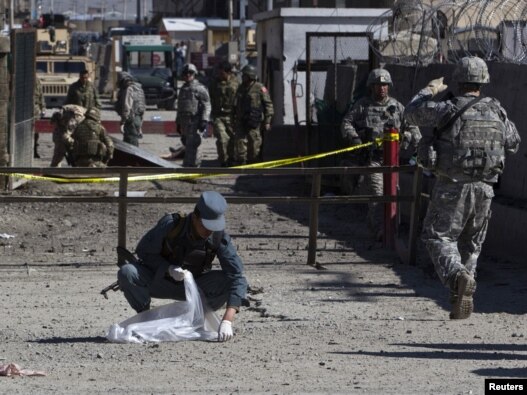 A policeman collects body parts after an attack at Camp Phoenix in Kabul on April 2.