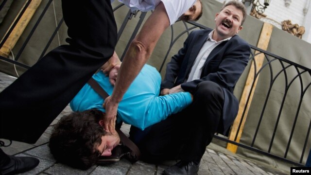 A Pussy Riot supporter is detained by security guards on the steps of the cathedral.
