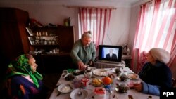 Women have their lunch as they watch Russian President Vladimir Putin on the television addressing the country's Federal Assembly on the Crimean referendum to reunify with Russia outside the peninsula's capital Simferopol.