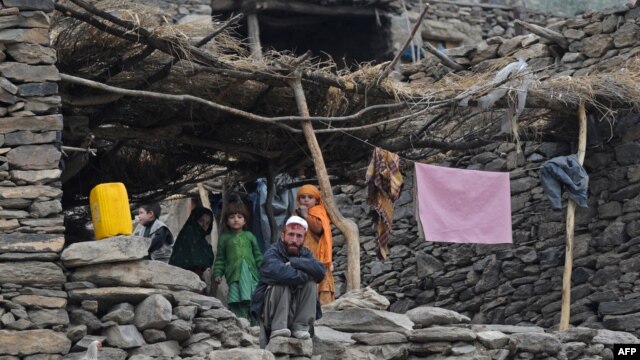 An Afghan family look on from their house in the mountains of Nuristan Province. Locals say Islamist militants have crossed the border from Pakistan and taken over whole districts.