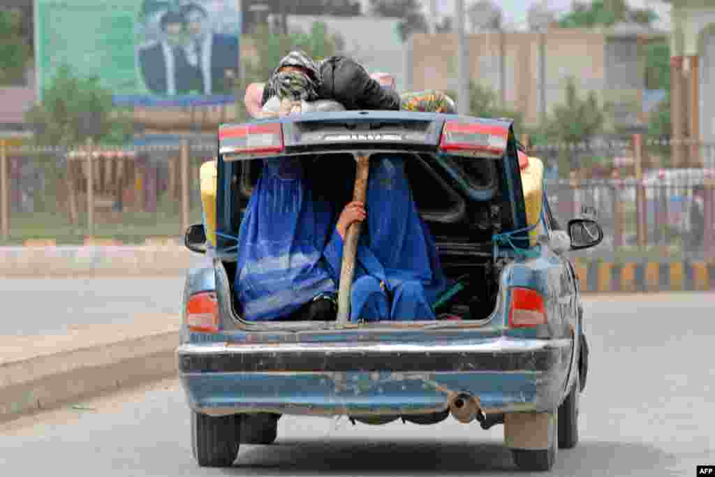 Polio vaccination volunteers ride in the open trunk of a car as they travel to administer the vaccine during a campaign in Afghanistan's Balkh Province. (AFP/Farshad Usyan)