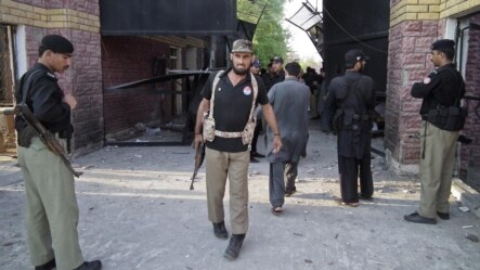 Pakistani policemen gather near a damaged jail gate after inmates escaped from the prison in the city of Bannu on April 15.