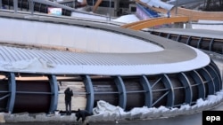 Workers paint the exterior of the track at the Sanki Sliding Center in preparation for the start of the Sochi Games last week.