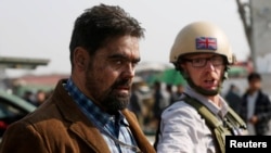 A British security official (right) escorts a survivor from the wreckage of a British Embassy vehicle after a suicide attack in Kabul on November 27.