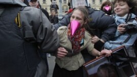 Police officers detain an opposition activist holding a portrait of Russian President Vladimir Putin, with a black ribbon commonly used for the deceased tied around it, during a protest on Putin's birthday in Moscow, 07Oct2012