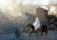 A man walks a horse carrying his wife through a street devastated by an earthquake in 2002 (AFP)