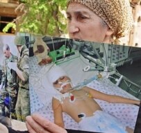 A relative of a child injured in the attack holds apicture outside the court on May 16 (ITAR-TASS)