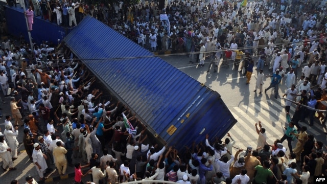Pakistani demonstrators topple a freight container placed by police to block a street during a protest against an anti-Islam film in Lahore on September 21.