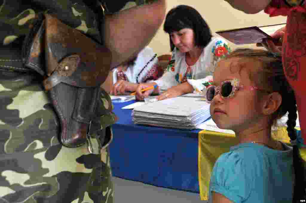 A young Ukrainian girl looks at a military serviceman taking part in the presidential election at a polling station in the city of Lviv.