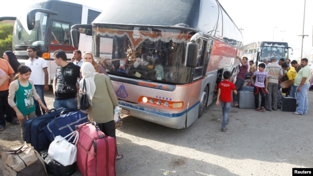 People unload their belongings in Baghdad from a bus that had traveled from Syria on July 20.
