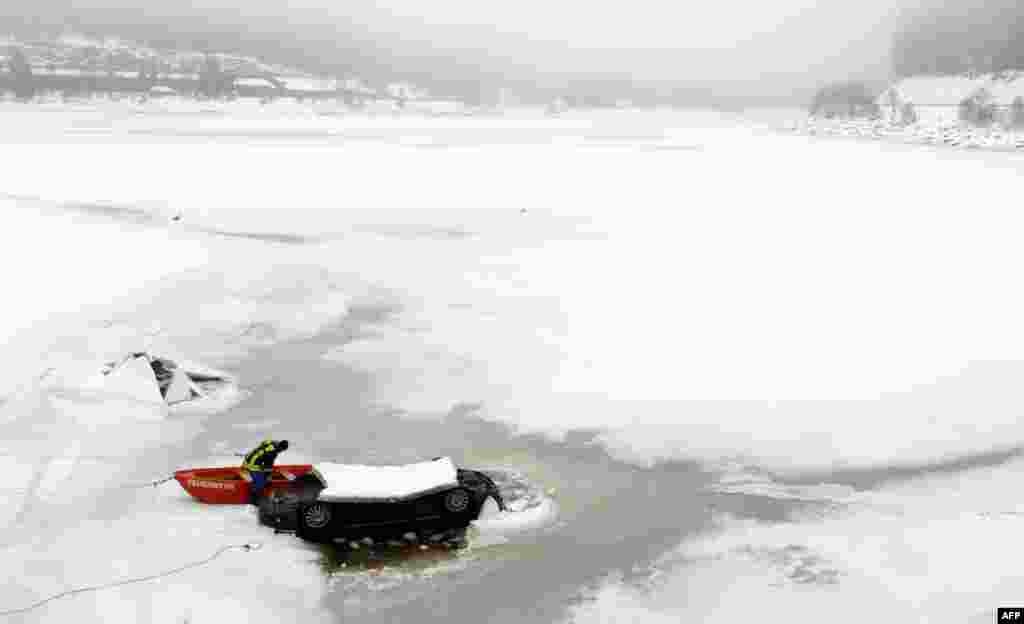 A firefighter works on the rescue of a car stuck in the frozen Schluchsee Lake in the Black Forest region of southern Germany. According to the police, the car was empty. (AFP/Patrick Seeger)