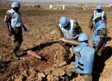 Lebanon/UN -- UN peacekeepers with the United Nations Interim Forces in Lebanon (UNIFIL) carry an unexploded Israeli 155mm artillery shell in an empty field near the southern Lebanese village of Bint Jbeil, 30Aug2006