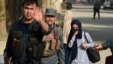 Female Afghan students who were trapped inside during the attack are escorted by Afghan police at the end of the nearly 10-hour raid at the American University in Kabul.