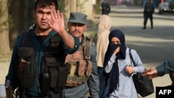 Female Afghan students who were trapped inside during the attack are escorted by Afghan police at the end of the nearly 10-hour raid at the American University in Kabul.