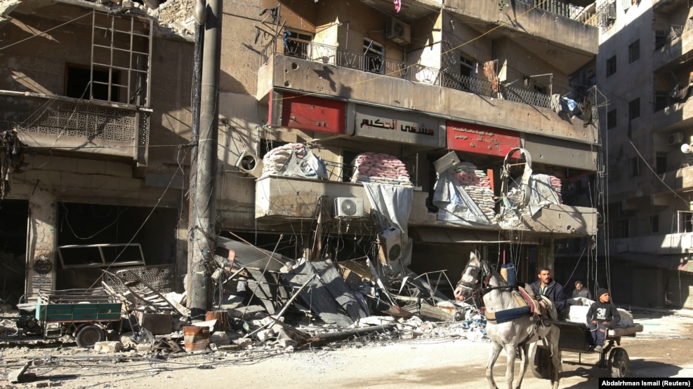 People ride a cart pulled by a horse near the damaged Hakim hospital, in the rebel-held besieged area of Aleppo.