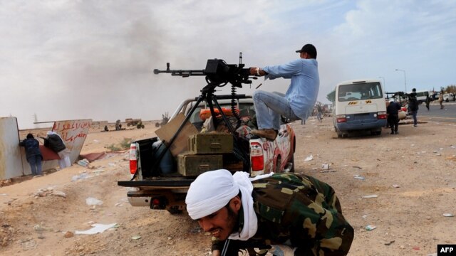 Libyan rebel fighters try to defend a gate of the north-central key Libyan oil town of Ras Lanuf as Muammar Qaddafi's loyalist forces approach their positions on March 10.