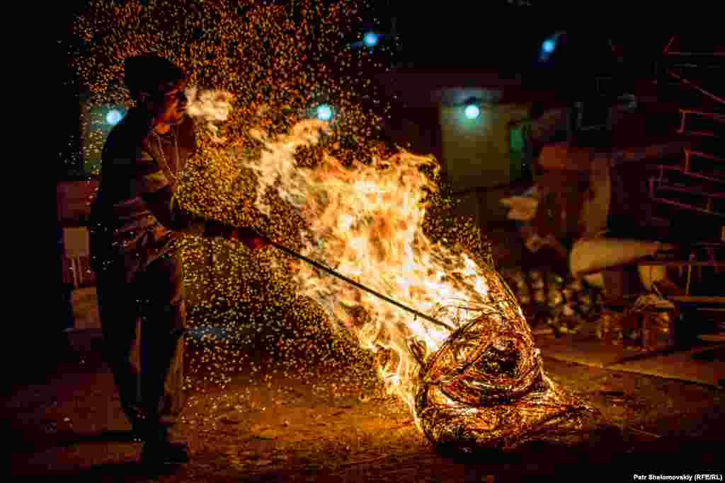 Raush, a refugee from Nagorno-Karabakh, burns cables at a scrap metal shop.