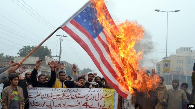 Pakistani demonstrators shout slogans beside a burning U.S. flag during a protest against drone strikes in Multan on January 3.