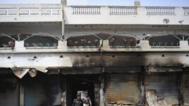 Pakistani police investigate the site of a burned market in a violence-hit western neighborhood of Karachi of July 8.