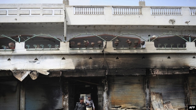 Pakistani police investigate the site of a burned market in a violence-hit western neighborhood of Karachi of July 8.