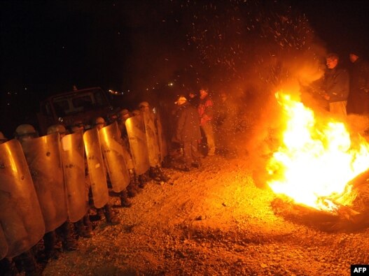 Kosovo Serbs stand in front of KFOR troops before dawn on October 20 as the NATO-led force tries to dismantle a roadblock near the village of Jagnjenica.