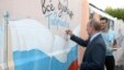 Russian President Vladimir Putin signs a mural featuring his country's national flag during an August 19 visit to Crimea, the Ukrainian peninsula that Moscow annexed in 2014. 