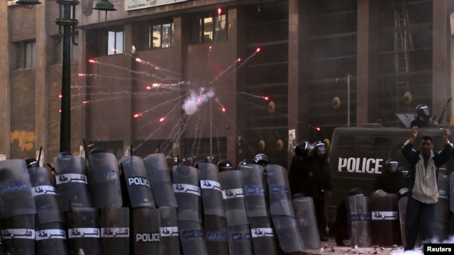 Egyptian riot police take cover as protesters throw flares and stones during clashes in Alexandria on January 25. 