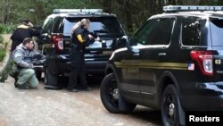 Police officers take cover behind vehicles during the standoff near Belfair, Washington.