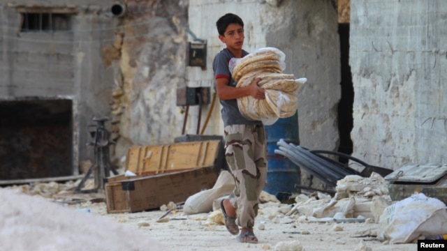 A boy carries bread as he walks in Latamneh city, which was hit by Russian air strikes, in the northern countryside of Hama.