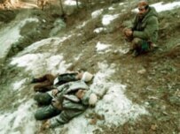 A Kosovo Liberation Army soldier beside the bodies of two elderly ethnic Albanians killed near Racak in 1999 (epa)