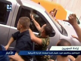 A TV video grab shows pro-regime supporters attacking a U.S. Embassy vehicle in Damascus on September 29.