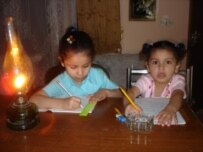 Iraqi children in Baghdad study by oil lamp (RFE/RL)
