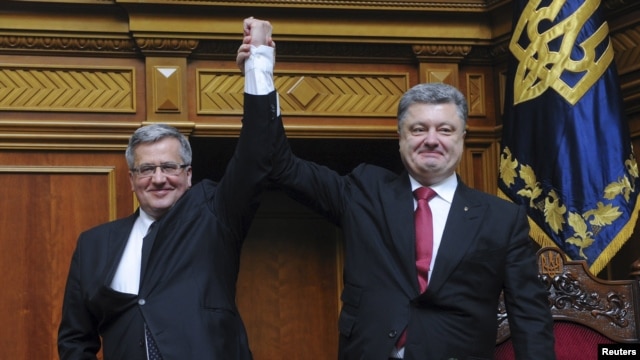 Ukrainian President Petro Poroshenko (right) raises aloft the hand of his Polish counterpart Bronislaw Komorowski during a session of the parliament in Kyiv on April 9. 