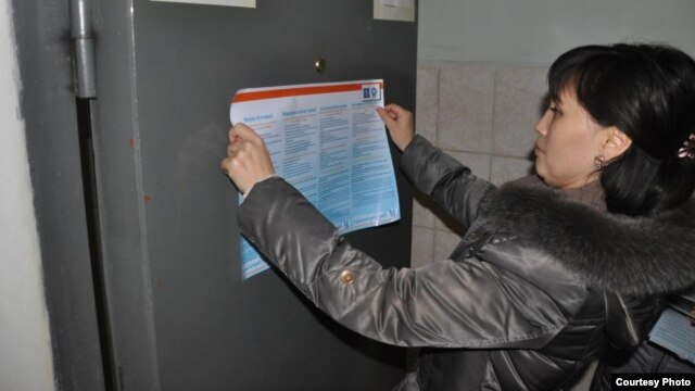 A social worker with the NGO Sana Sezim hangs up a flyer on how to avoid becoming a victim of human trafficking and labor exploitation at a police station in Shymkent, Kazakhstan.
