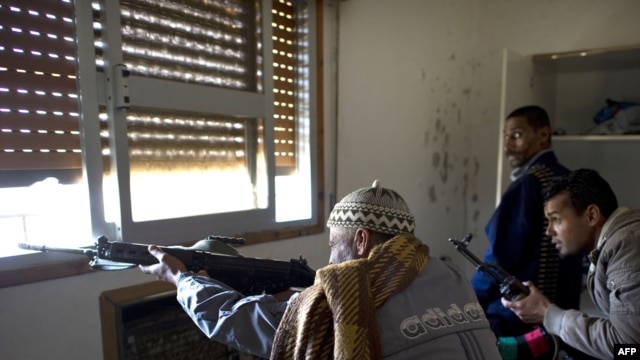 Libyan rebel fighters fire on loyalist snipers from a window in a trashed house on Tripoli Street in Misurata on April 20.