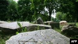 Gravestones from a destroyed Jewish cemetery near a monument to Jews killed during World War II