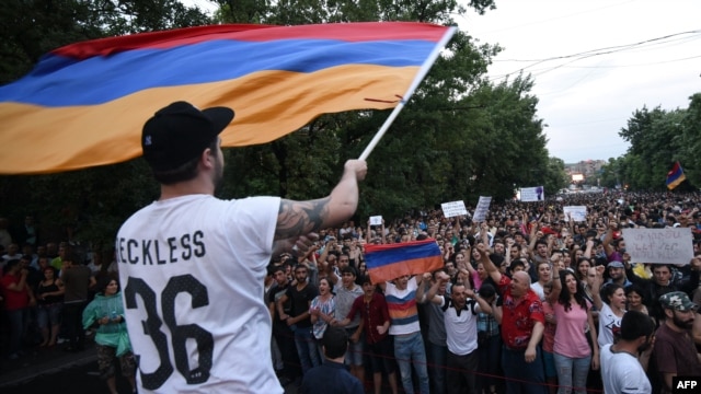 A demonstrator waves an Armenian flag as others shout slogans during a protest against an increase of electricity prices in Yerevan on June 25.
