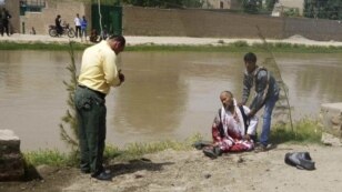 A wounded man sits near the scene of a suicide attack near a government compound in Baghlan Province on May 20 that killed at least 14 people.