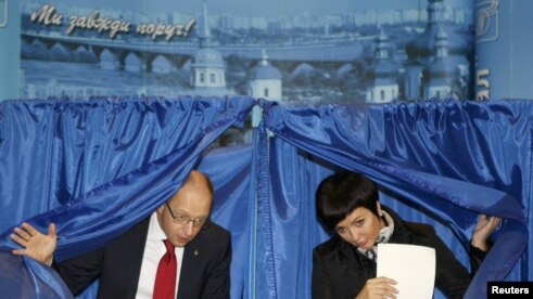Arseny Yatsenyuk (left), heads a union of opposition parties, and his wife Theresa leave voting booths at a polling station during the parliamentary elections in Kiev.