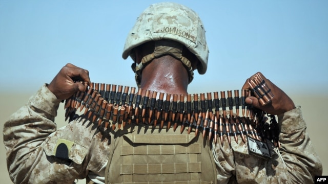 A U.S. Marine removes a bandolier of ammunition from around his neck during a group shooting lesson for Afghan police in Helmand Province.