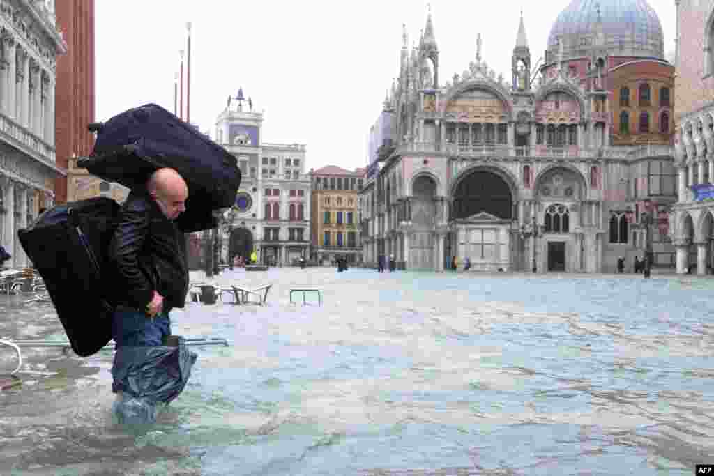A man carries luggage across a flooded St. Mark's Square in Venice. Rain and wind hit the north of Italy on November 11, sparking flooding that reached 150 centimeters in the ancient city. (AFP/Marco Sabadin)