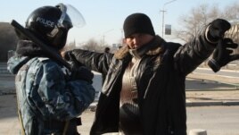 Полицей қала тұрғынын тексеріп тұр. Жаңаөзен, 19 желтоқсан 2011 жыл. (Көрнекі сурет)